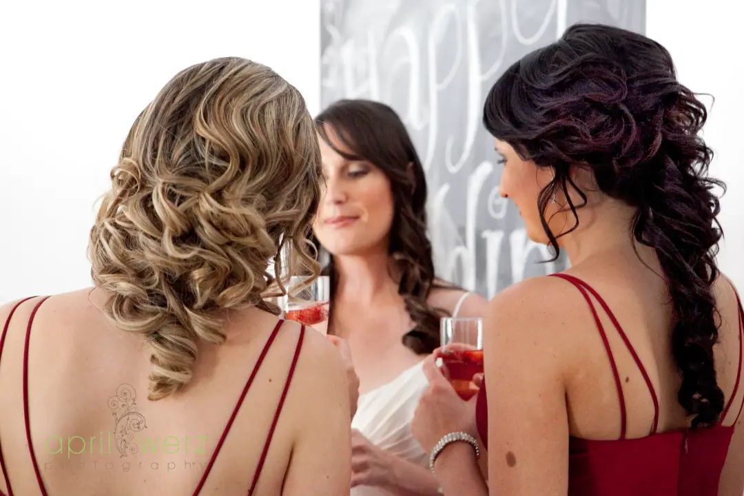 Two guests at the reception in red, one in brushed out blonde curls and one with long dark waves
