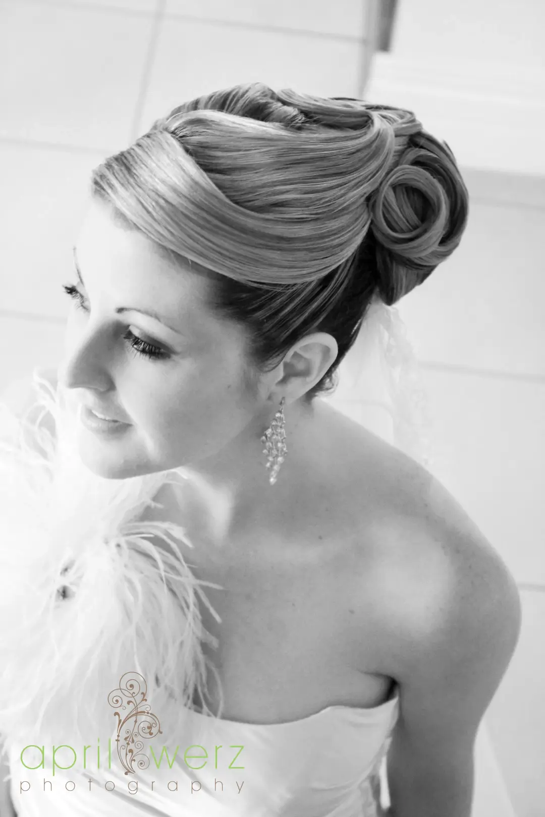 Vintage rolled and pinned updo photographed in profile, worn with a feather wrap and drop earrings