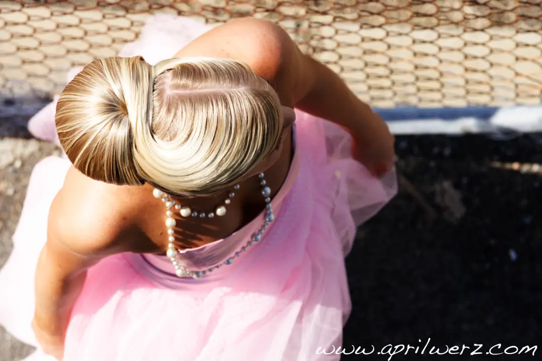 Blonde hair wound into a sleek high bun, photographed from behind with a pearl strand