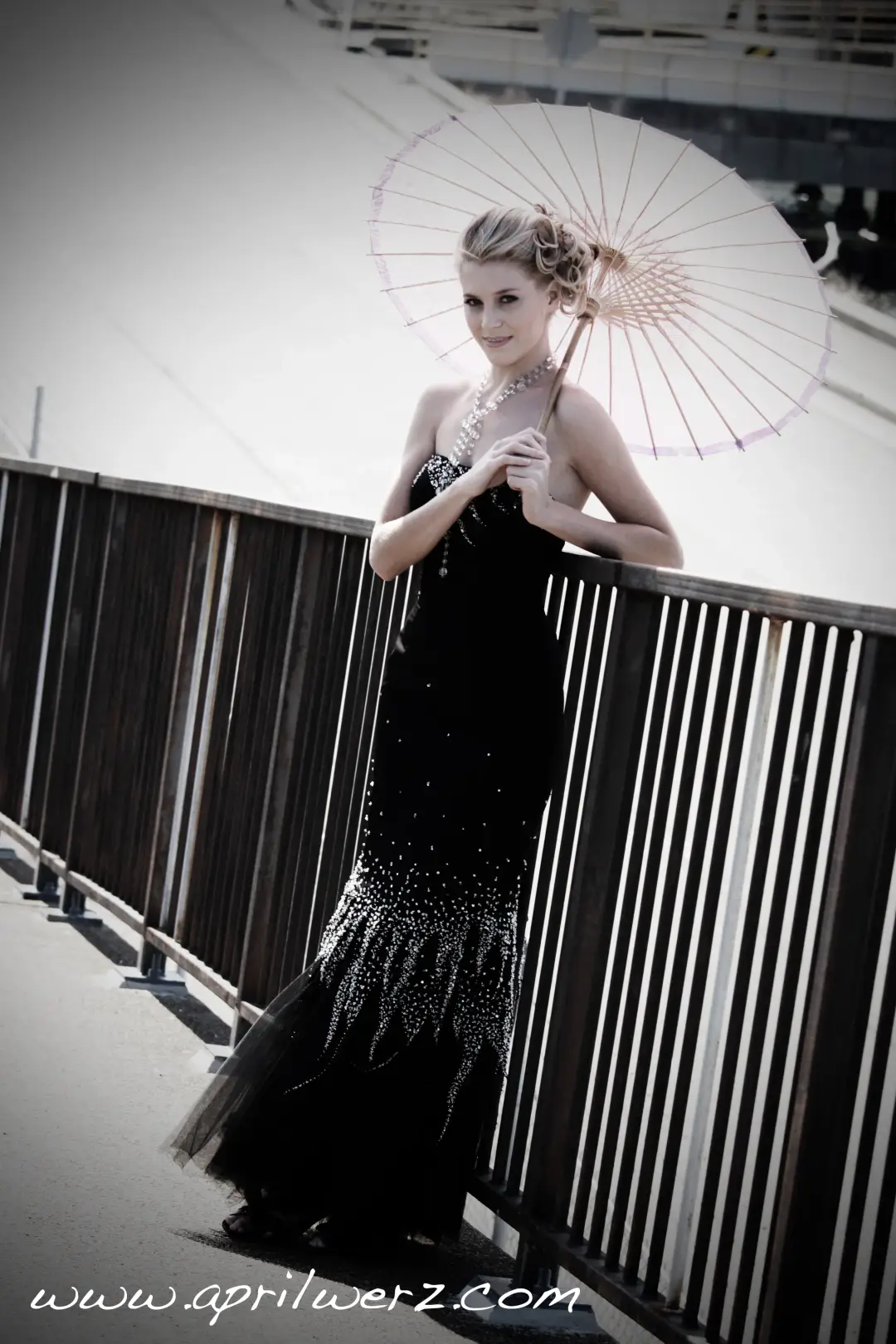 Guest with a parasol in a black beaded gown, her blonde hair pinned into a braided updo