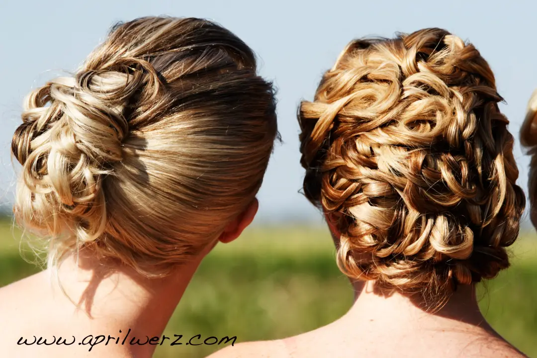 Two bridesmaids photographed from behind, both wearing curled and twisted updos