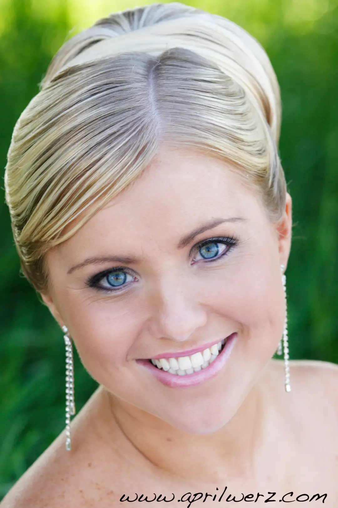 Bride with her blonde hair rolled into a smooth updo, wearing long diamante earrings