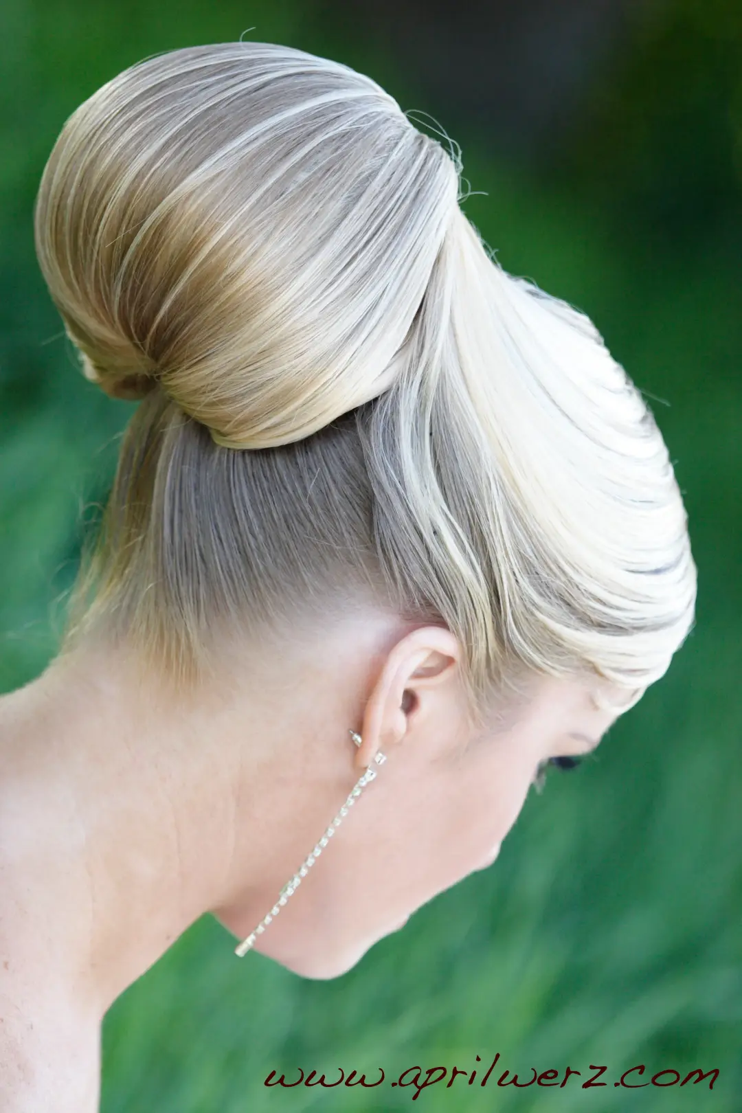 Back view of a sleek blonde high bun with a wrapped base and a swept fringe