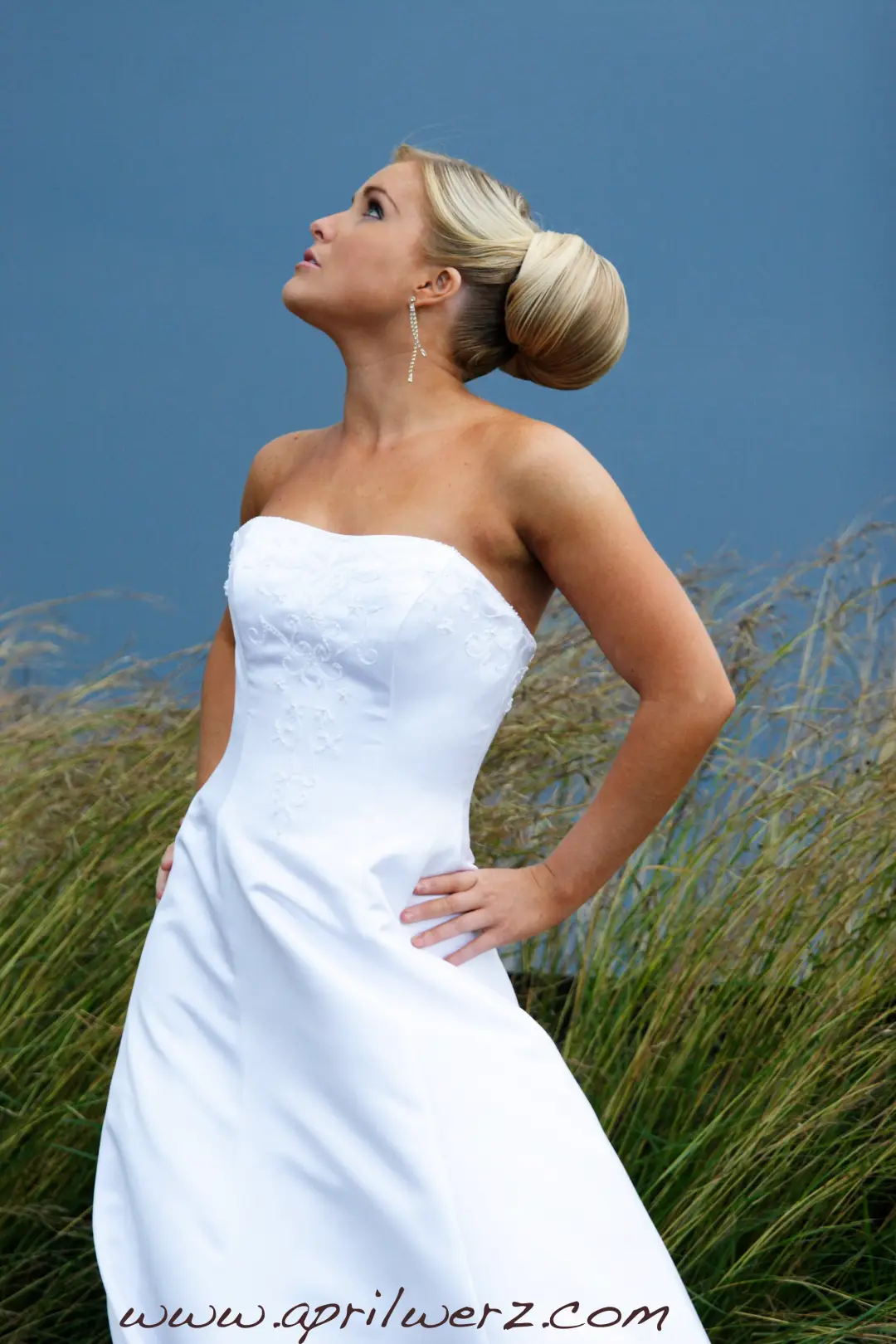 Bride in the dune grass with her blonde hair set in a sleek high bun