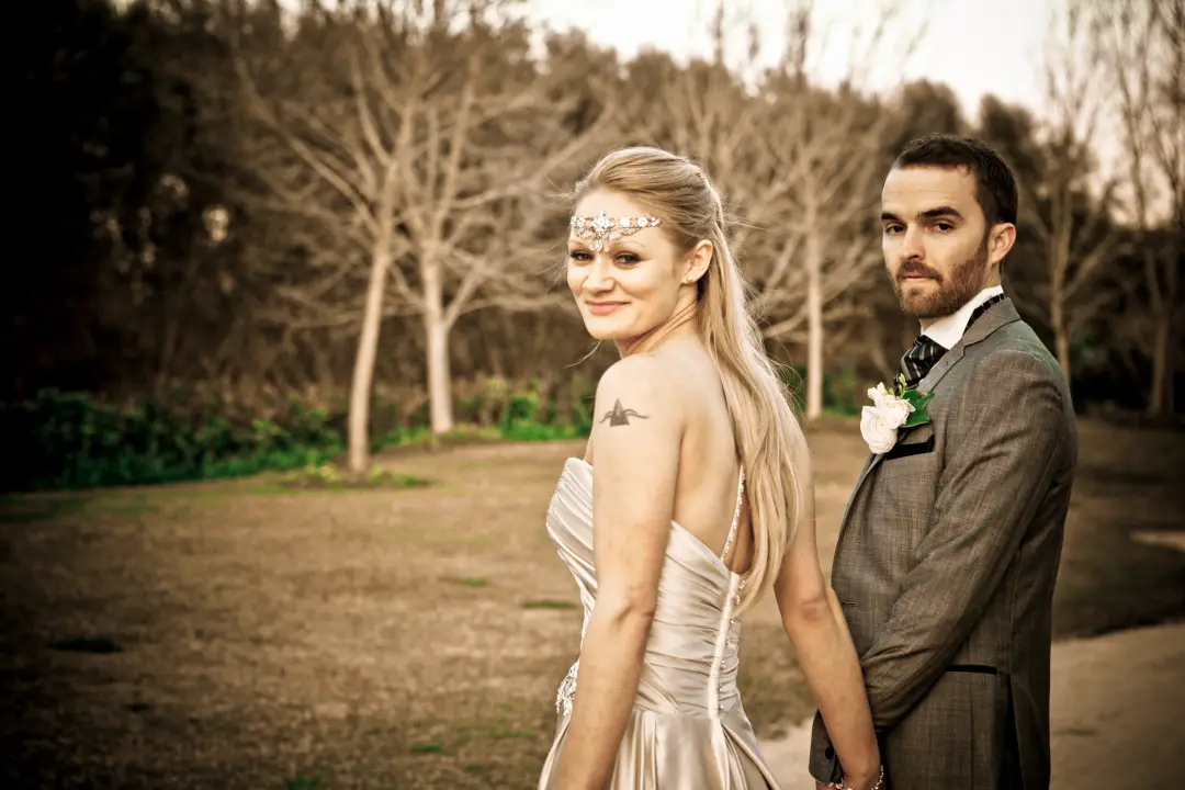 Bride and groom back to back in a paddock, her long hair worn down with a beaded browband
