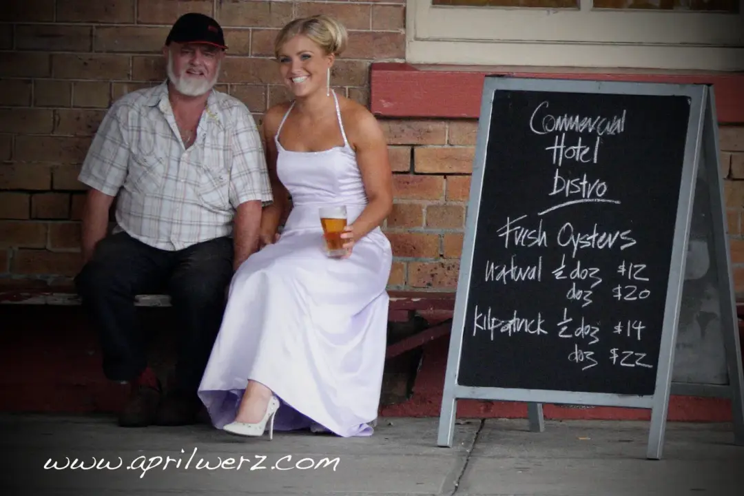 Guest in a white dress outside a country pub, her blonde hair pinned into a soft updo