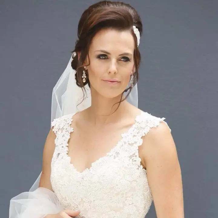 Bride in a lace gown with her dark hair pinned into a low updo beneath a veil