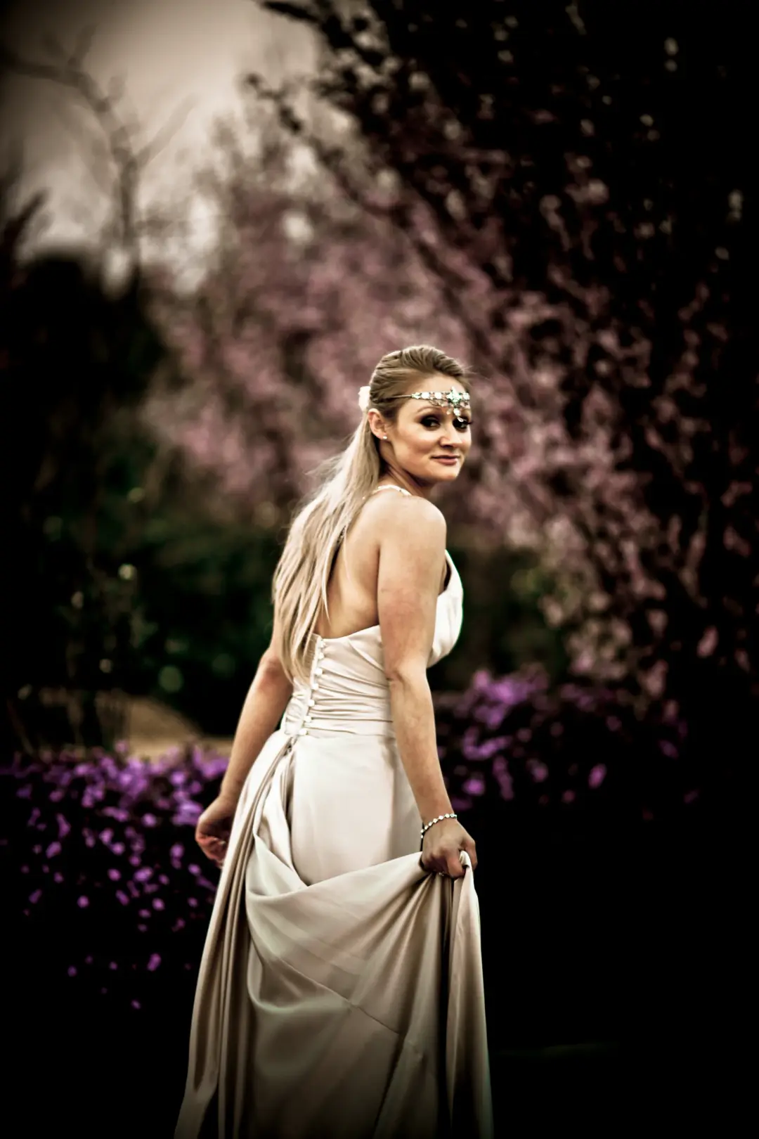 Guest under blossom in a satin gown, her long blonde hair worn down with a jewelled browband