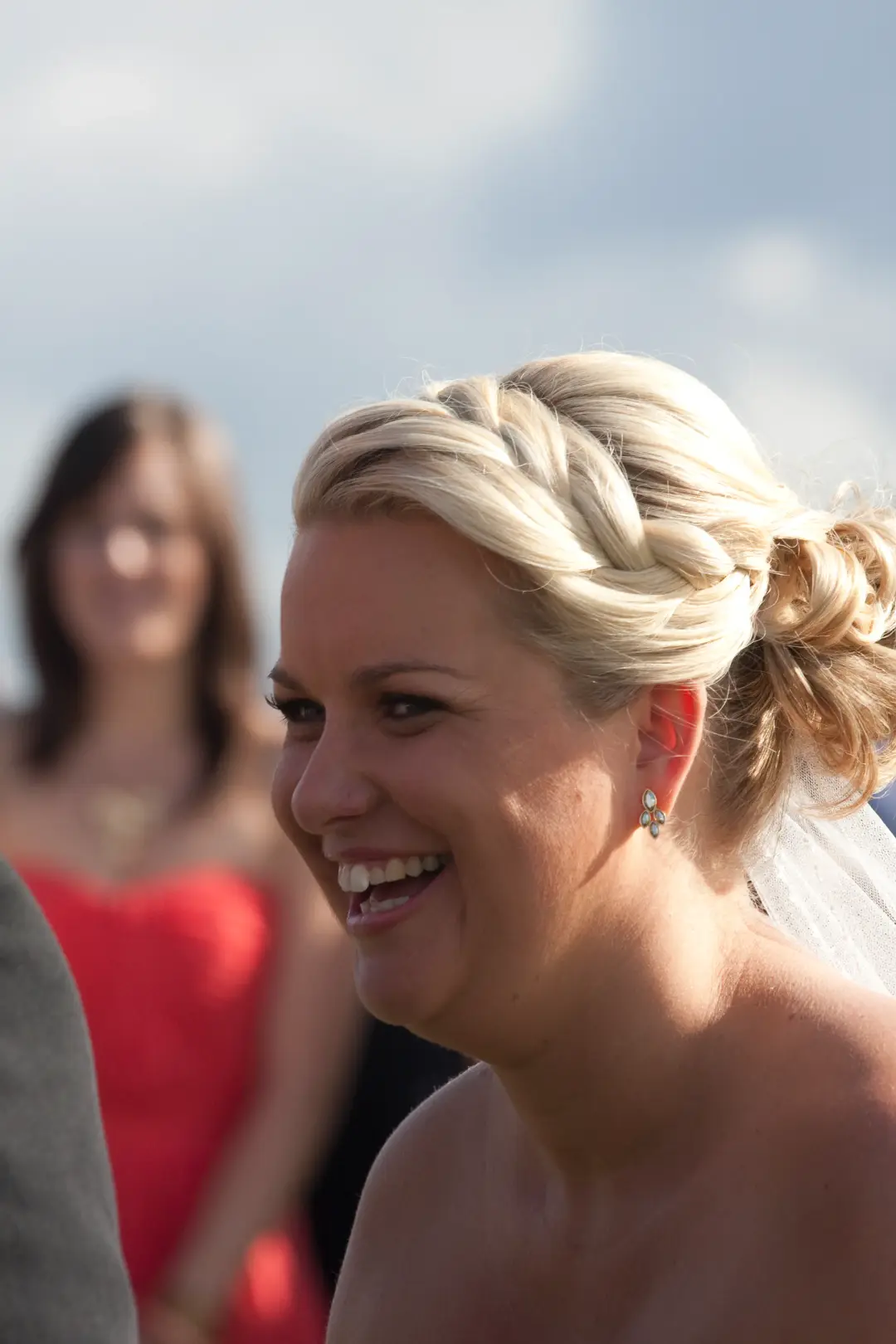 Bride laughing at the ceremony, her blonde hair worn in a braided crown over a low bun