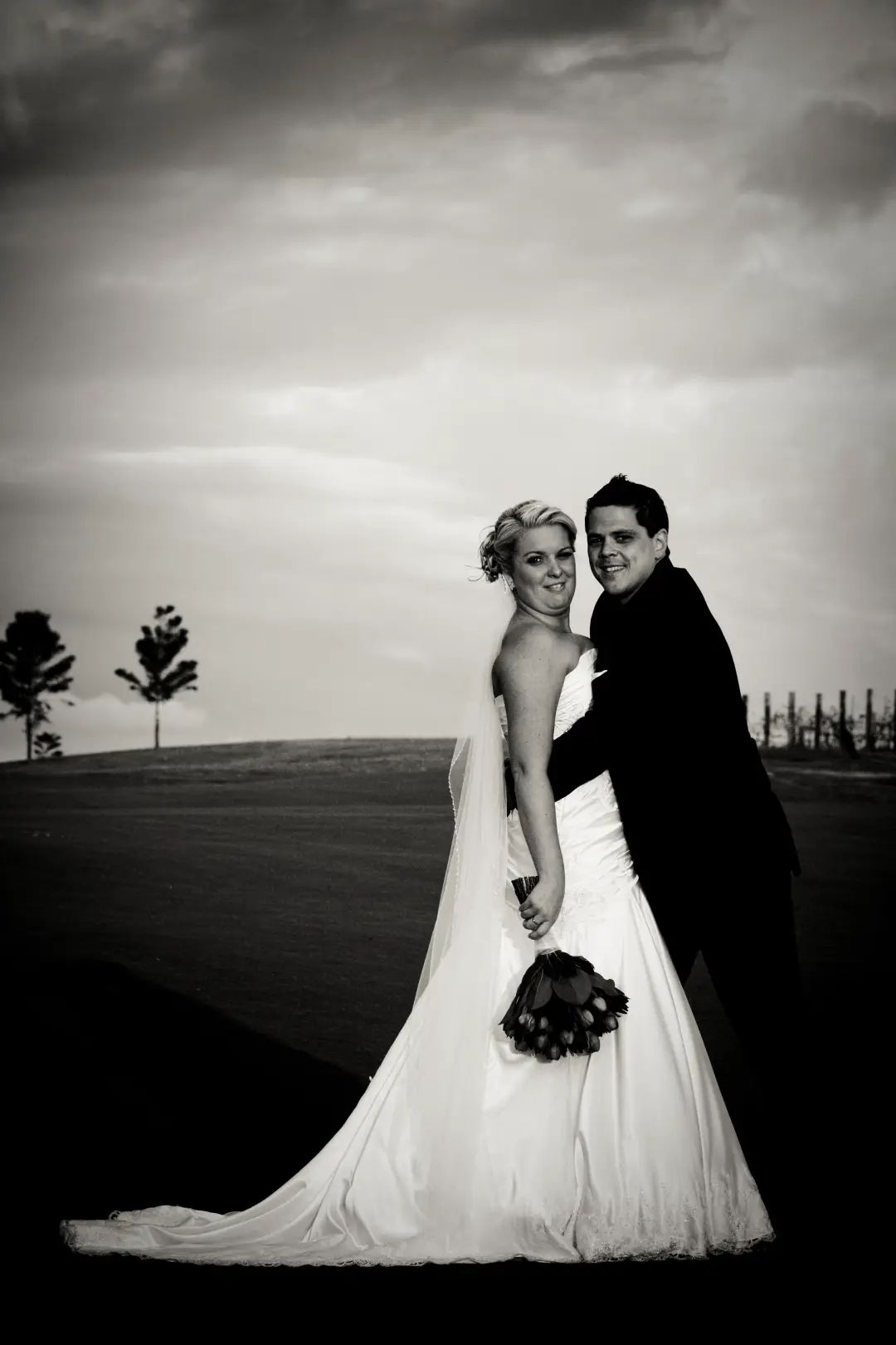 Bride and groom on the fairway, her blonde hair pinned into a low updo above a fitted gown
