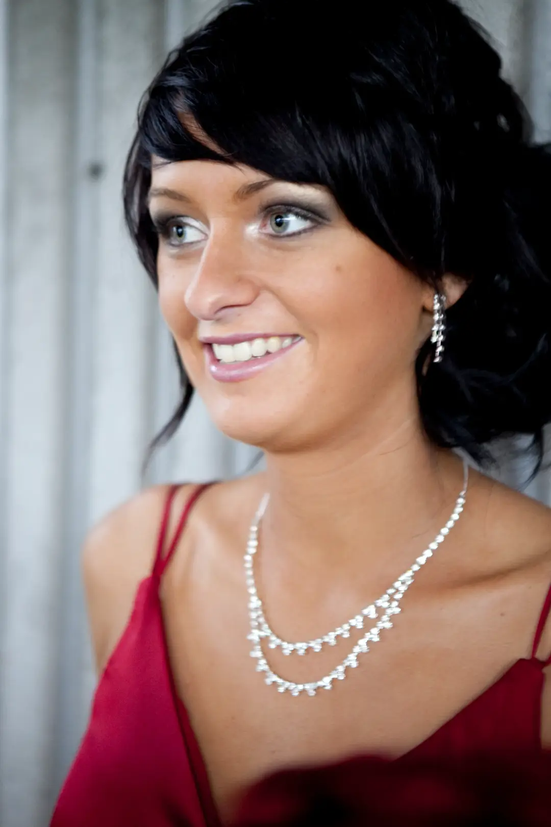 Guest in a red dress with dark hair swept to one side, wearing soft daytime makeup