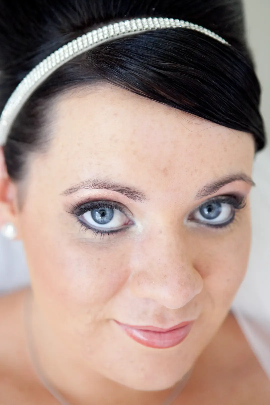 Close portrait of bridal makeup with a soft grey liner and a nude lip, worn with a diamante headband