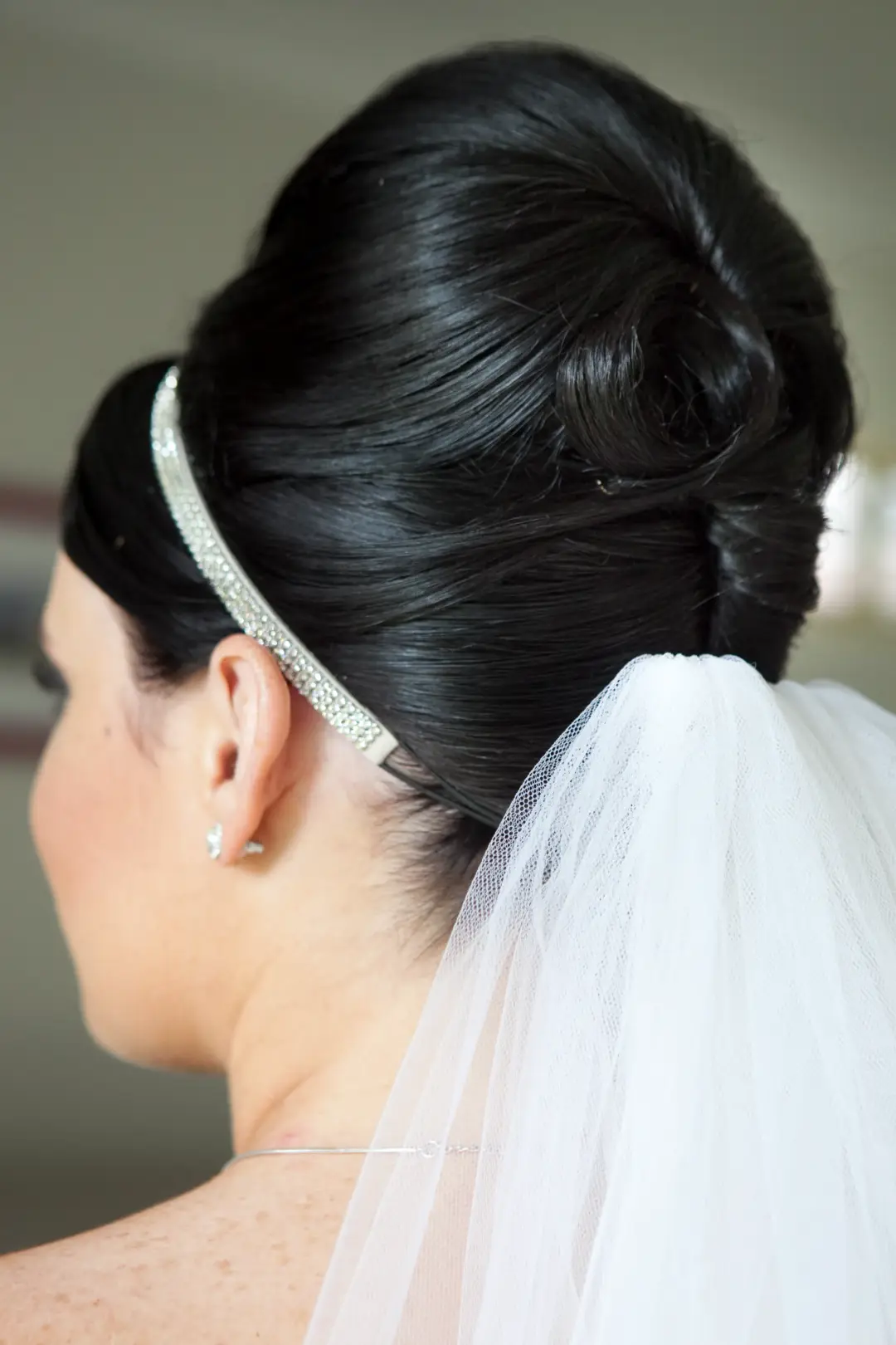 Dark hair swept into a high French roll with a crystal headband and a cathedral veil