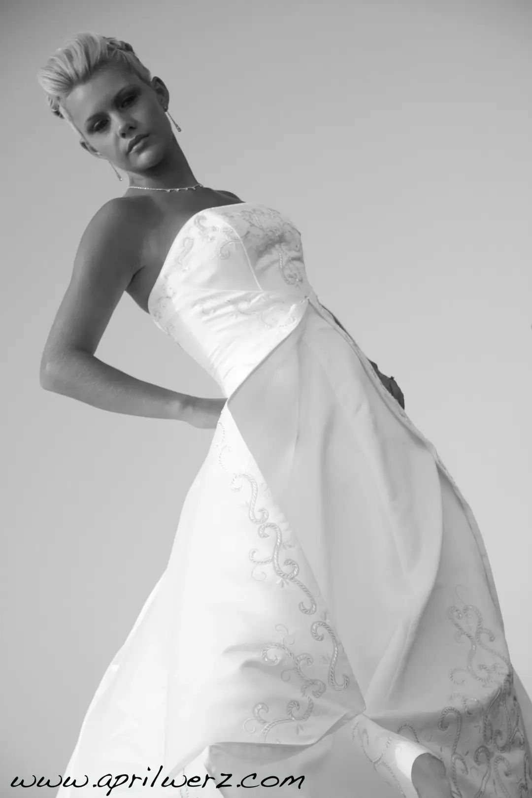 Bride in a strapless gown with a short sculpted blonde cut, photographed against the sky