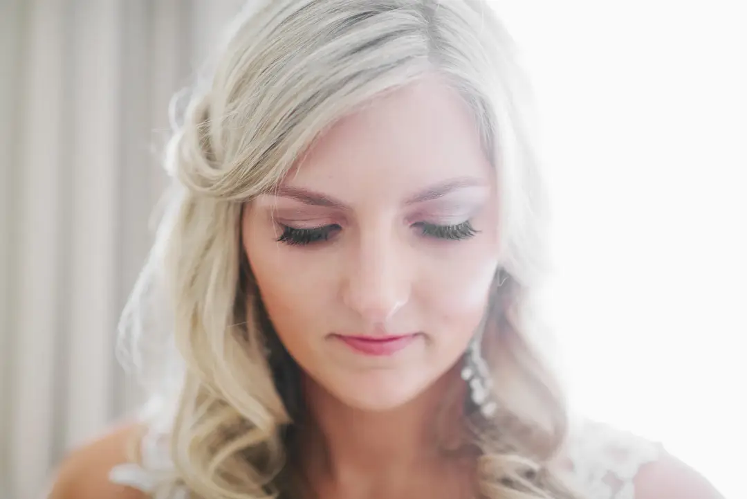 Bride with a soft twisted half up style and glowing natural makeup with a pink lip