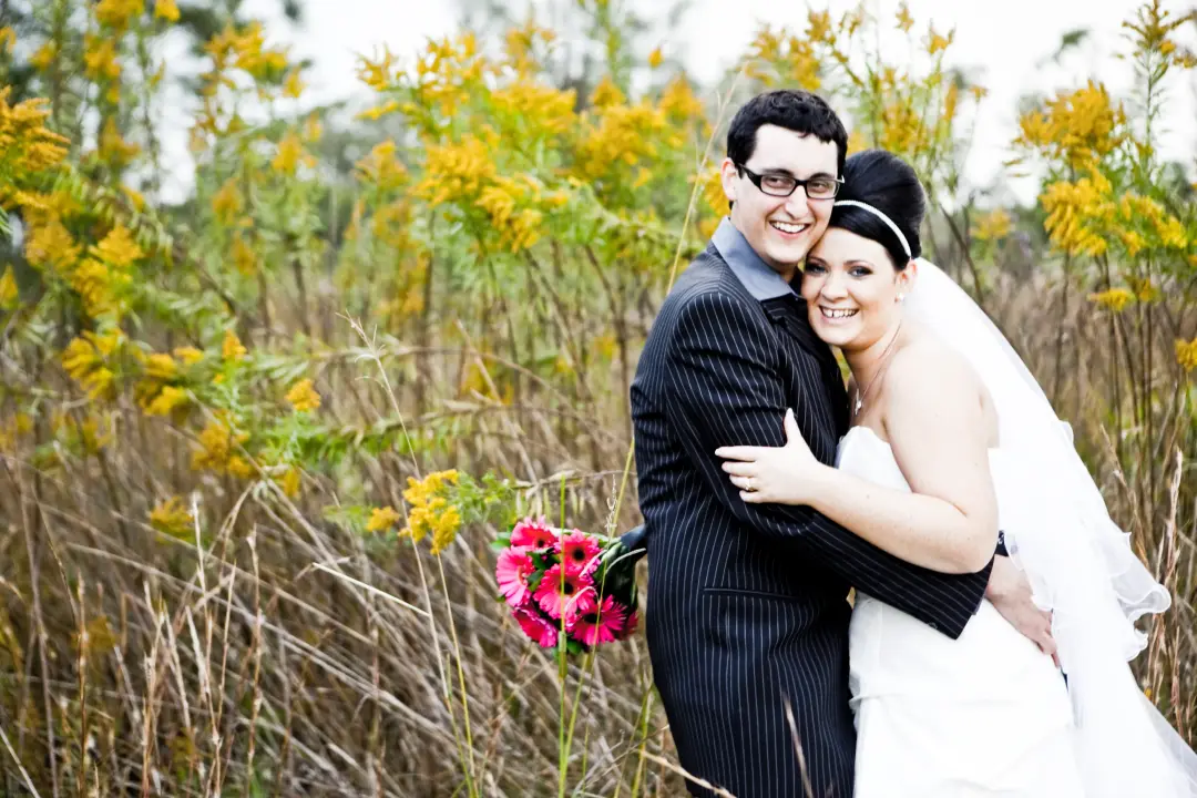 Bride and groom laughing in the wattle, her dark hair pinned back with a jewelled headband