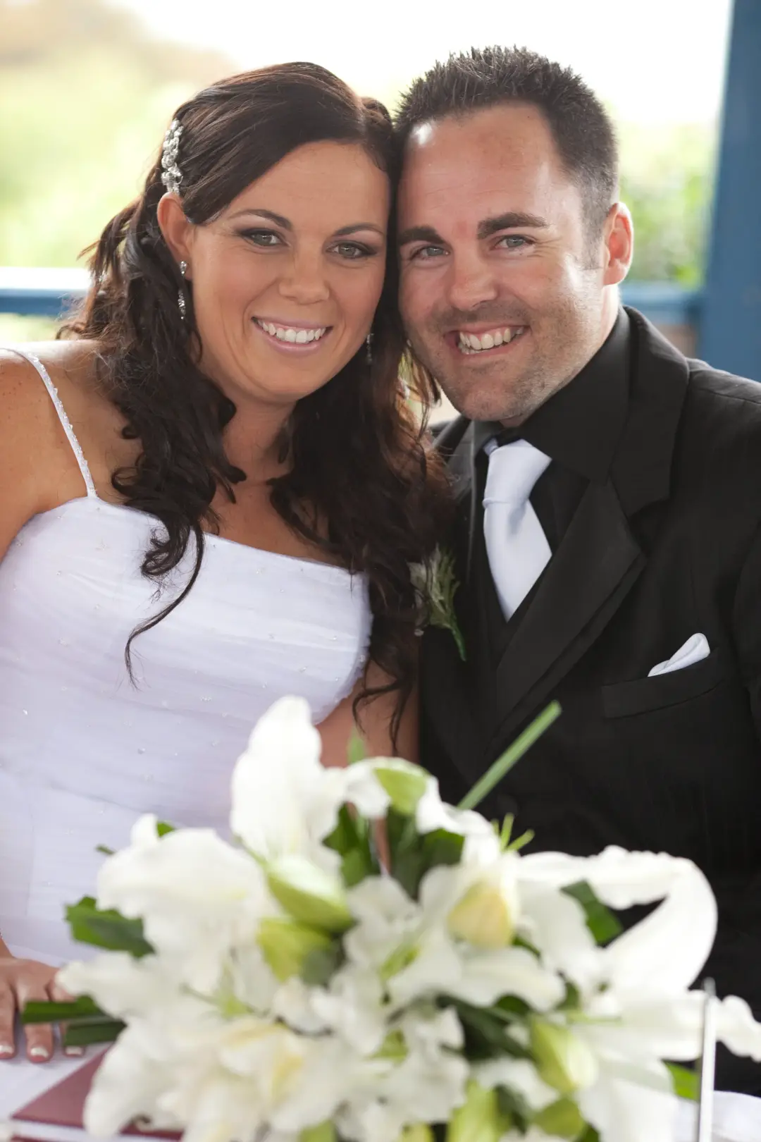 Bride and groom at the signing table, the bride's dark hair worn half up with a crystal comb