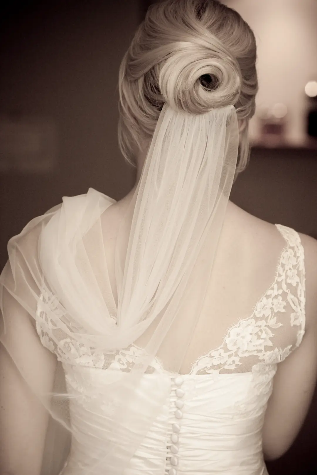 Back view of a vintage rolled upstyle worn under a soft veil with a lace gown