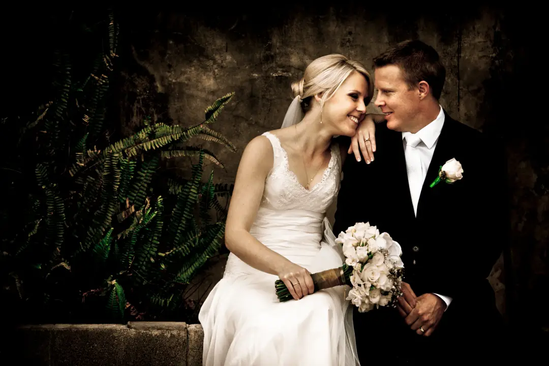 Bride and groom seated together, her blonde hair pinned into a low twist