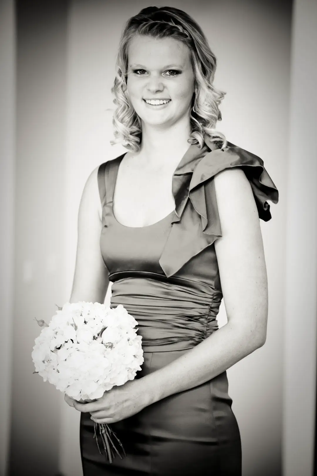 Bridesmaid in a satin gown with blonde curls worn down and pinned back
