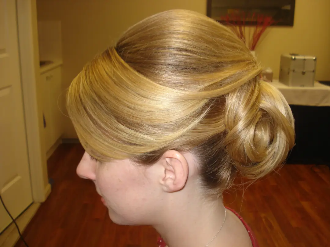 Side view of a sculpted low bun with a swept fringe, styled on blonde hair