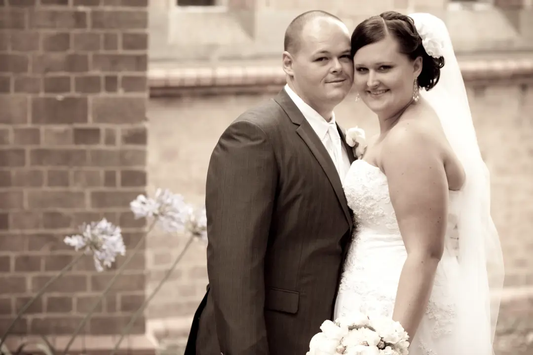 Bride and groom outside a brick church, the bride's hair pinned up under a veil