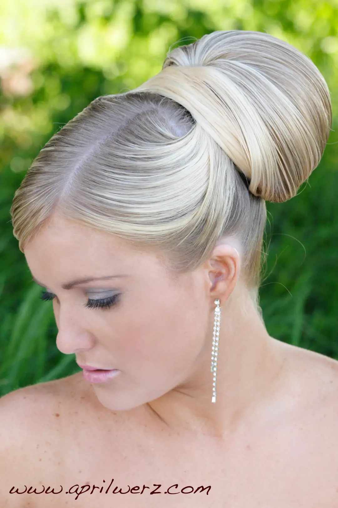 Sleek high bun with a wrapped finish, styled on blonde hair and worn with long drop earrings