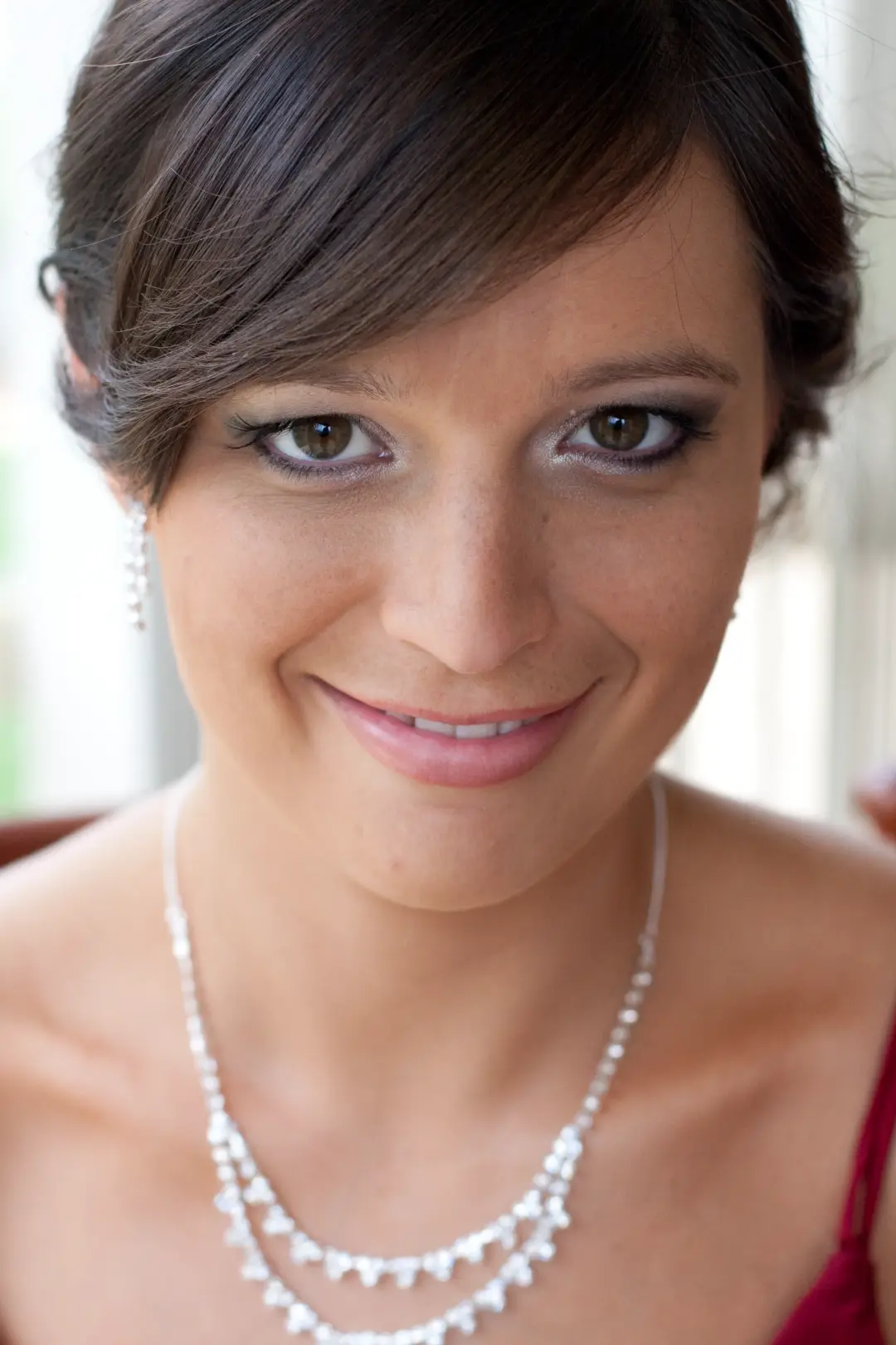 Guest with dark hair swept into a soft side style, wearing a warm neutral eye and a nude lip
