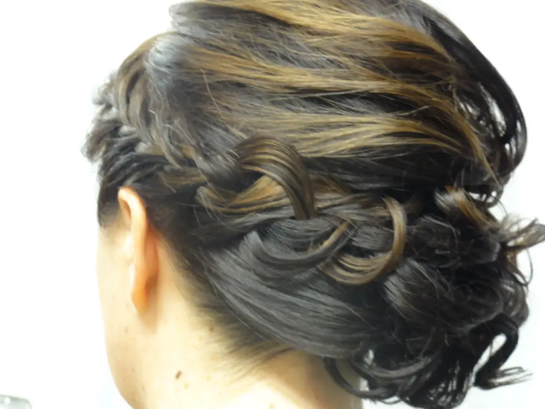 Close view of a dark twisted and curled upstyle pinned at the nape