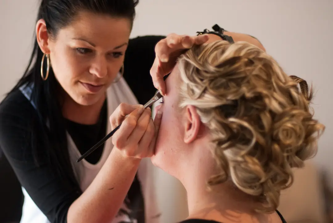Eye makeup applied to a bride whose blonde curls are already pinned into an updo