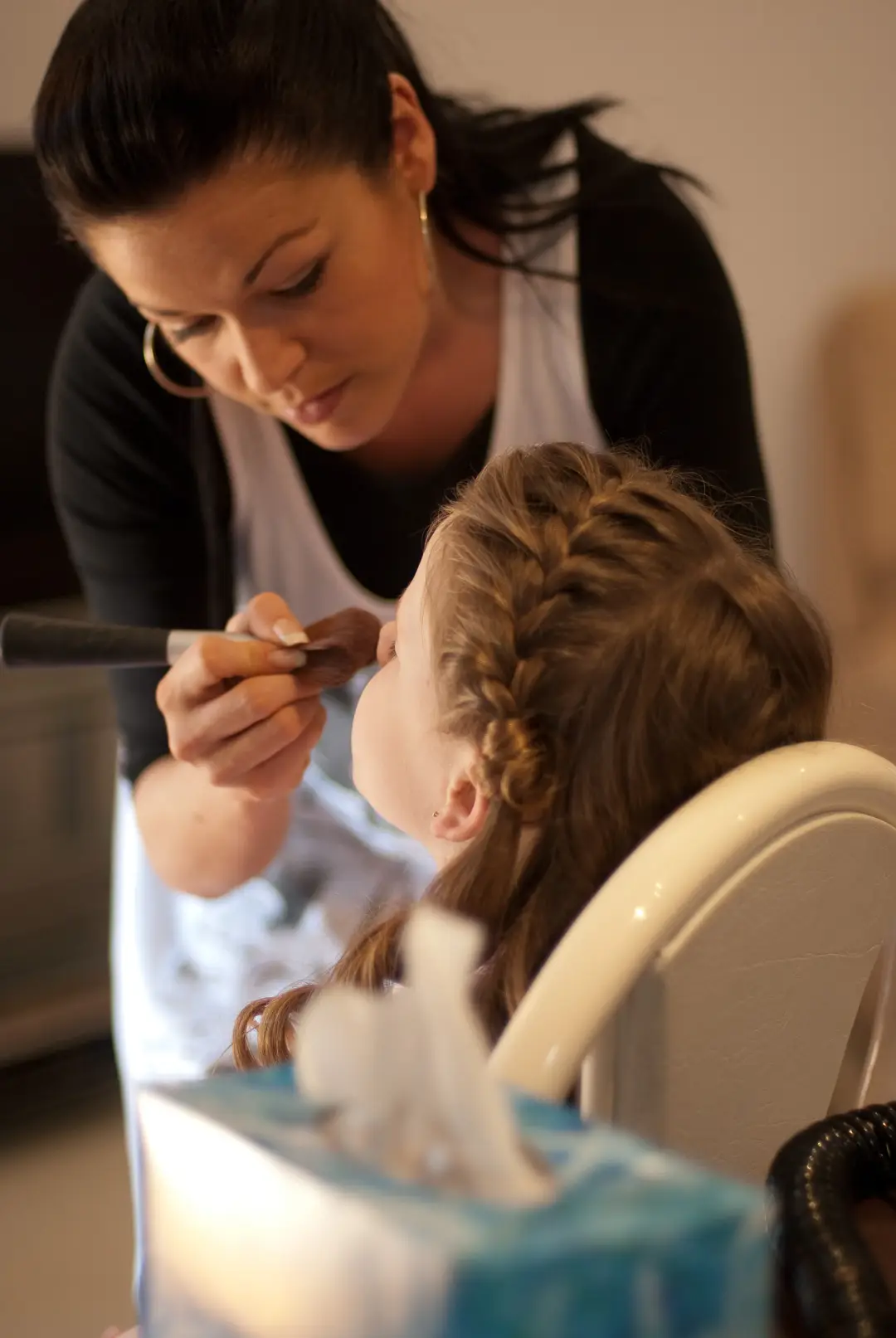 Flower girl having her makeup done, her hair braided along the crown