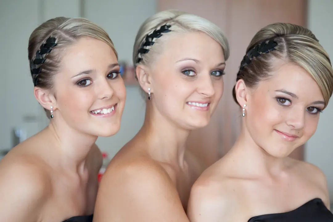 Three bridesmaids styled together in braided crowns, each wearing soft smokey eye makeup