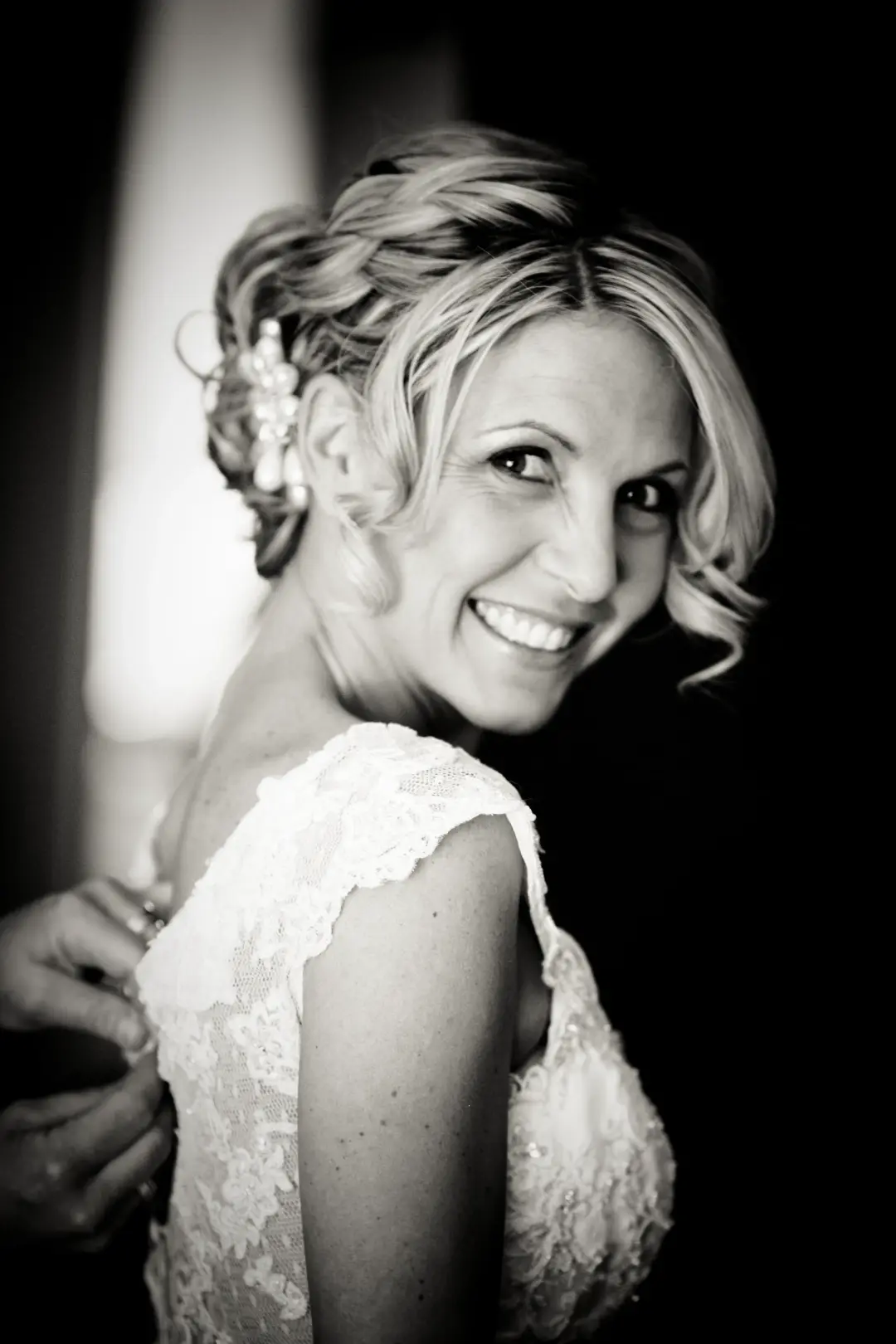 Bride laughing over her shoulder, her blonde hair pinned with a small floral comb