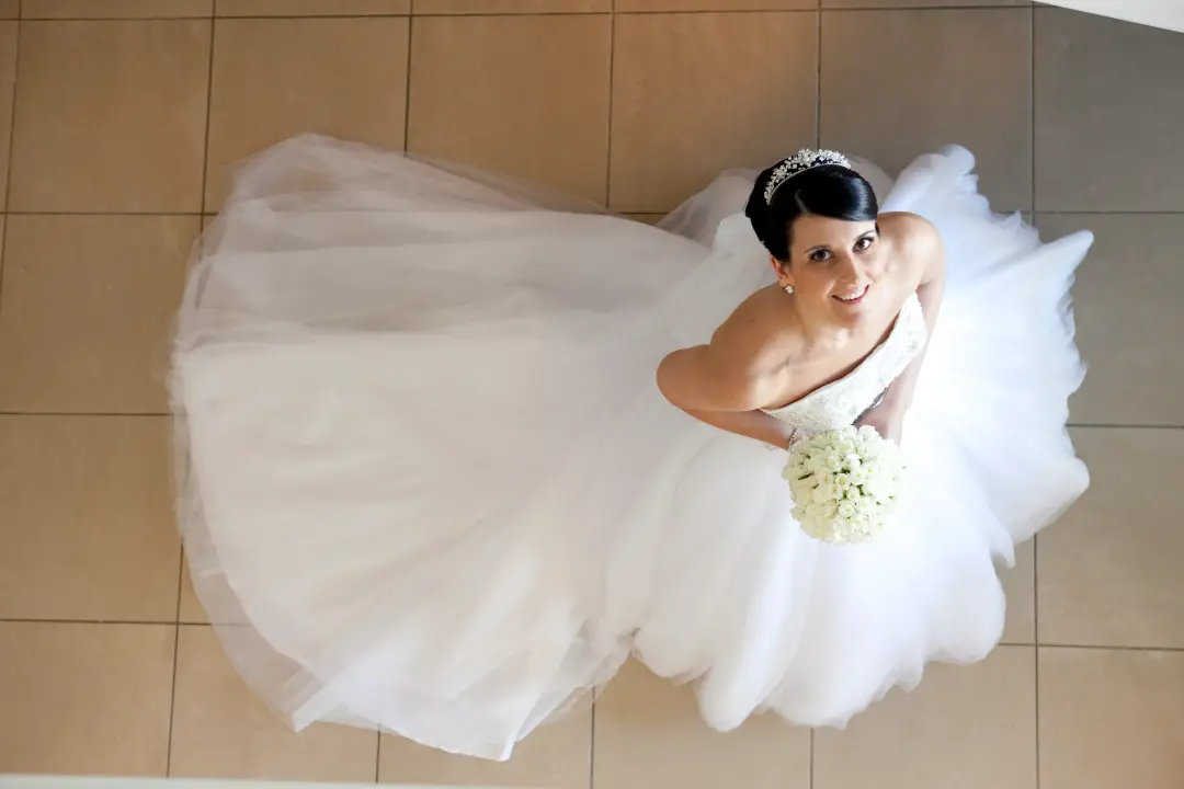 Bride photographed from above with her tulle skirt spread out, hair pinned under a tiara