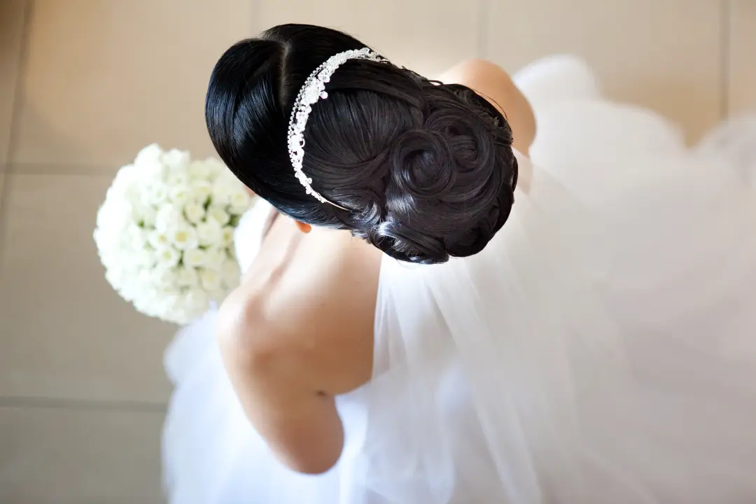 Back view of a smooth dark chignon with a diamante headband and a veil
