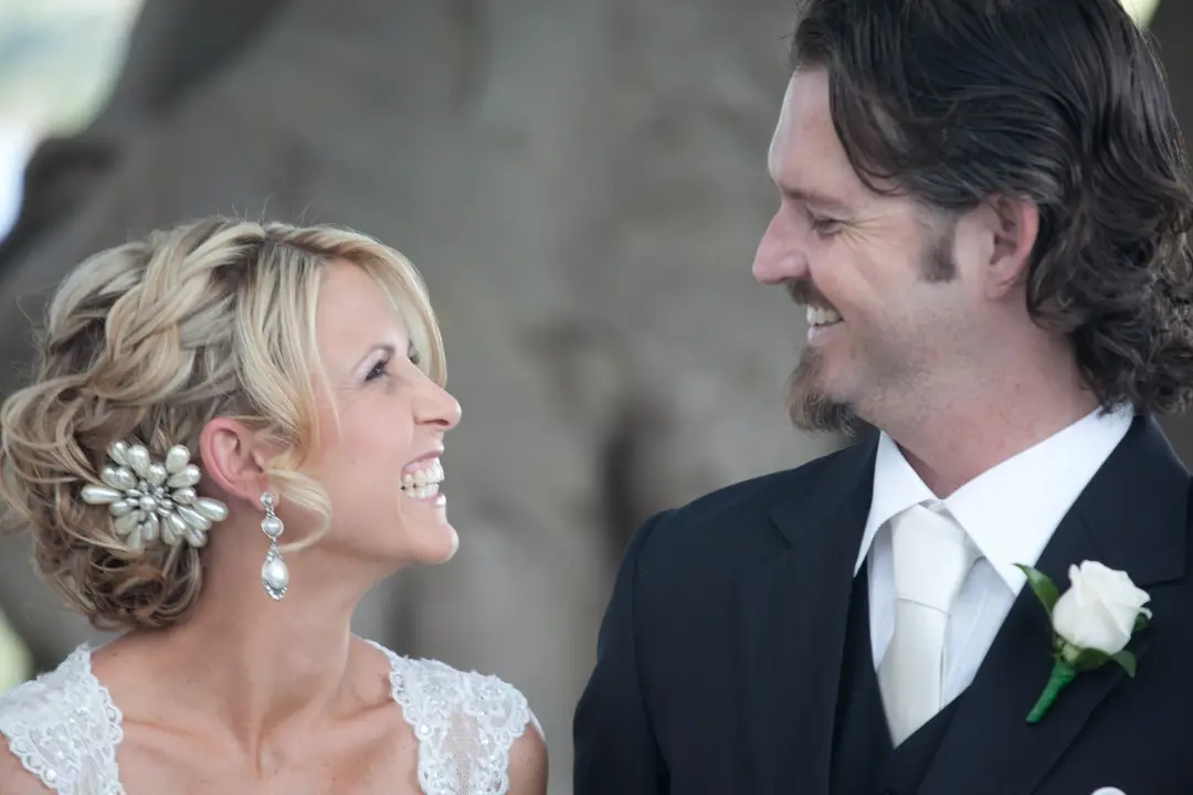 Bride and groom laughing together, her blonde hair pinned with a crystal floral comb