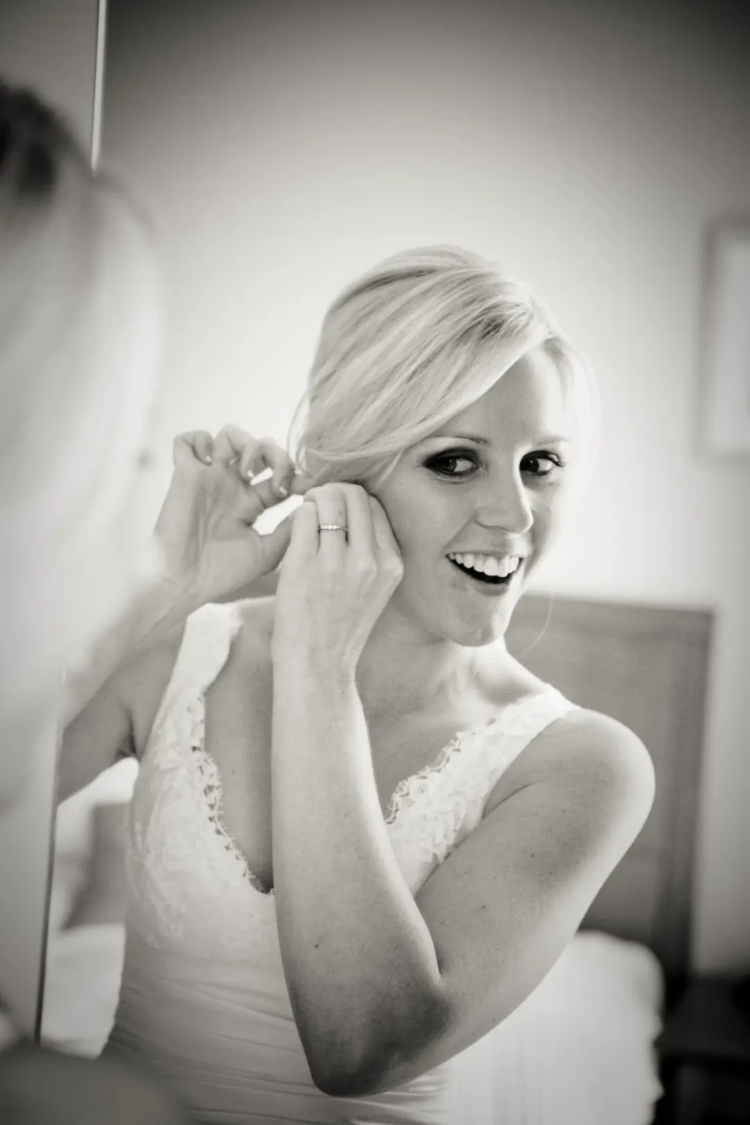 Bride putting in an earring, her blonde hair pinned back with a swept fringe and a smokey eye