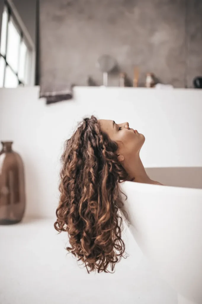 Curly Hair - Women laying in bath with hair hanging 